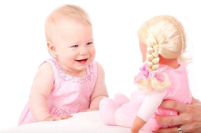 holčička smějící se na panenku